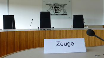 Bild zeigt den Blick auf eine Richterbank im Sitzungssaal des Landesarbeits Baden-Württemberg und im Hintergrund das Landeswappen